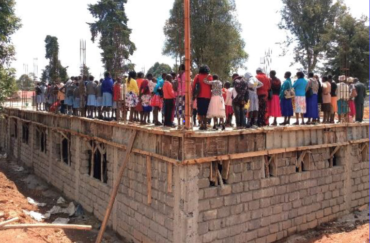 Photo of Kenyans standing on building site